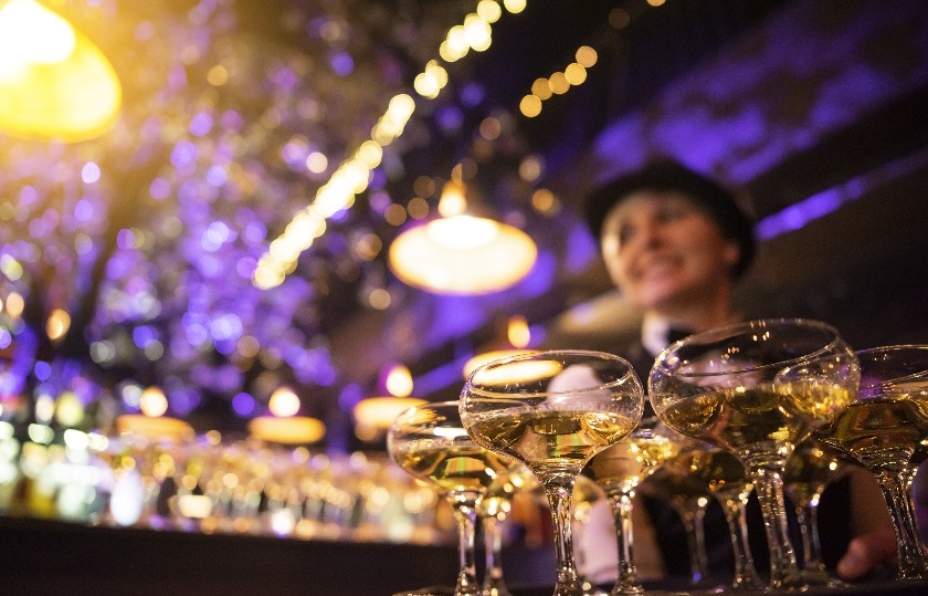 Happy waitress holding a tray full of glasses or welcome drinks at an event jpg